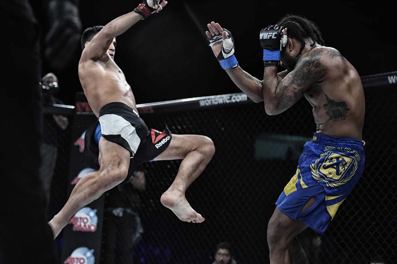 mma fighter delivering a huge flying kick to his opponent