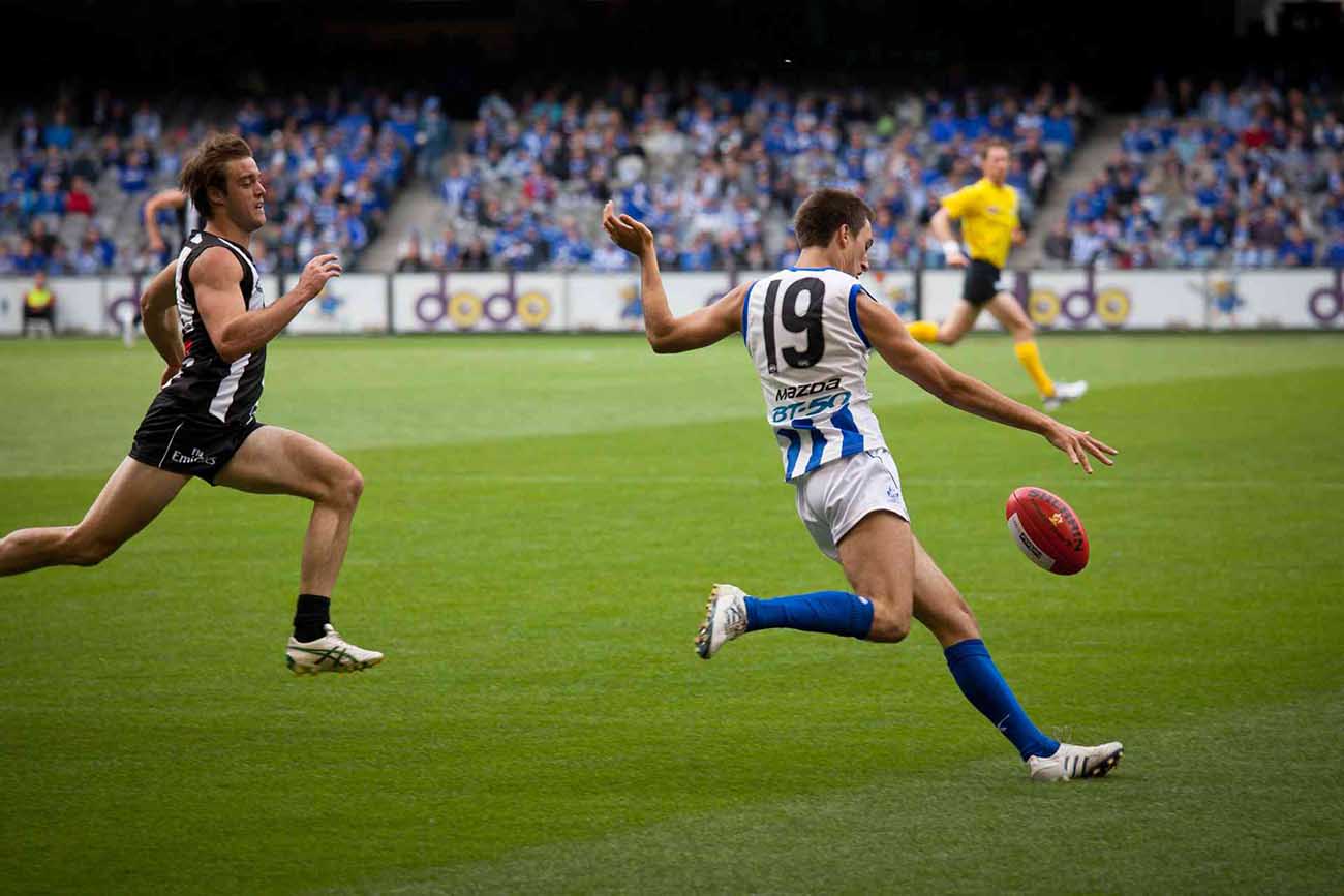 Australian football player getting ready to punt the ball